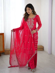 Woman wearing a bright pink traditional outfit with intricate designs indoors.