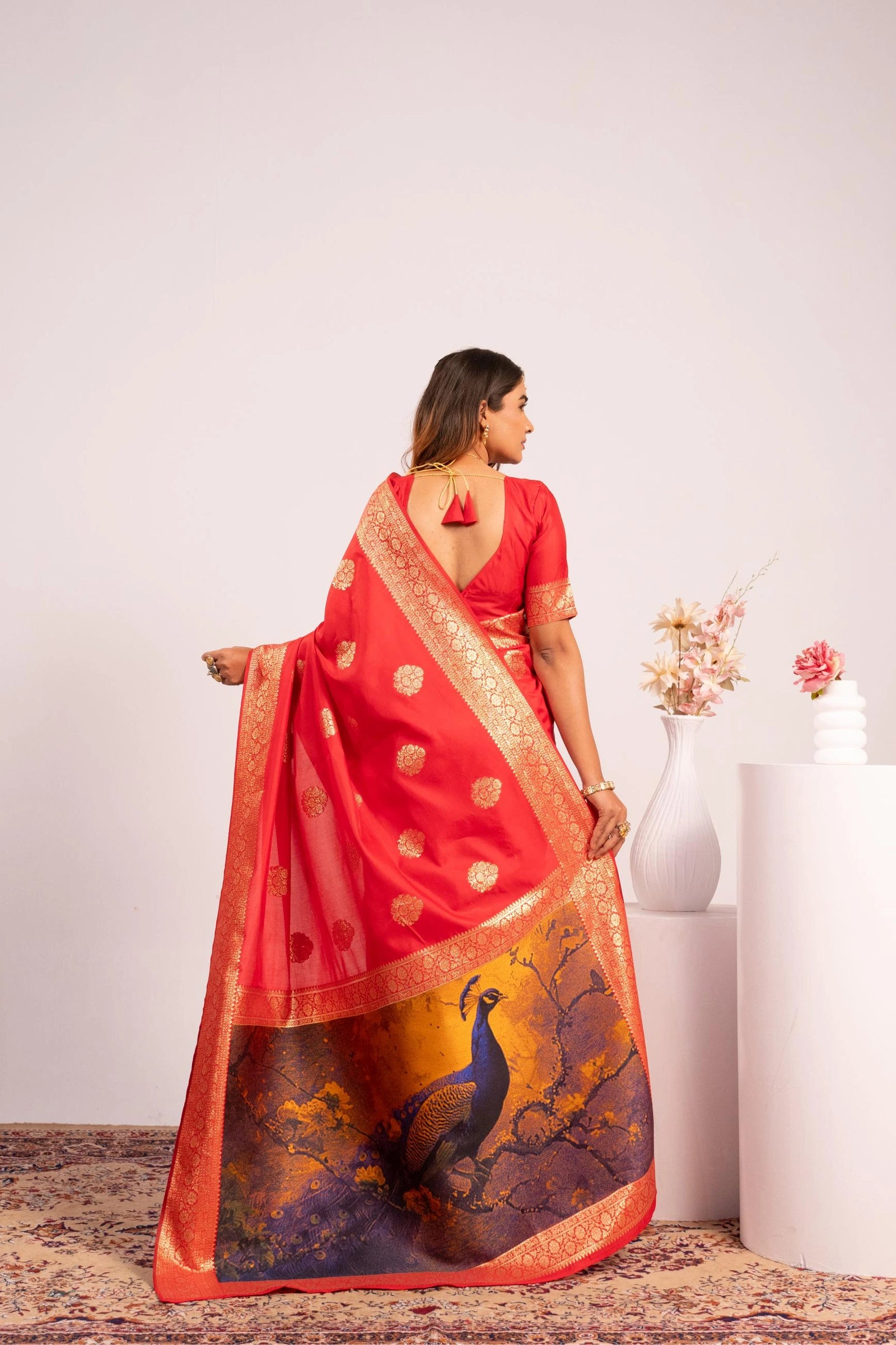 Woman wearing a red saree with peacock design on a white background