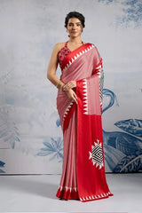Woman wearing a red and white saree with a geometric pattern against a decorative background