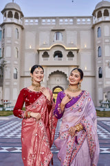Two women in traditional sarees standing in front of a decorative building.