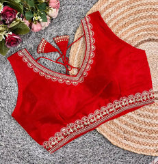 Red blouse with white embroidery on a textured surface with flowers in the background
