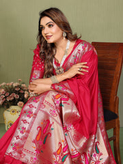 Woman in a traditional pink saree with floral patterns sitting on a wooden chair.