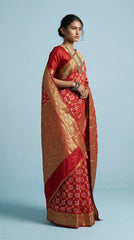 Woman wearing a red and gold saree on a light blue background
