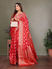 Woman wearing a red saree with white patterns against a plain background