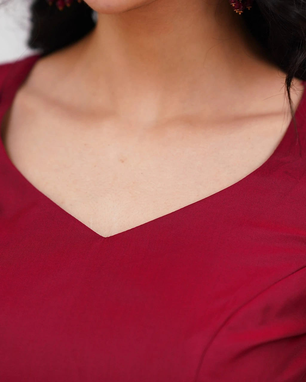 Close-up of a person wearing a red garment with a V-neckline.