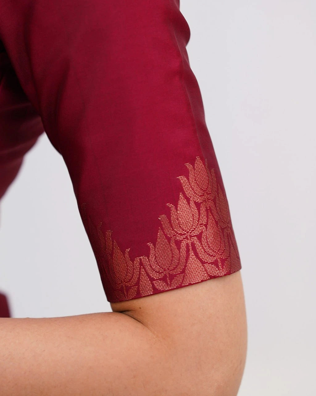Close-up of a maroon sleeve with intricate red floral embroidery on a white background