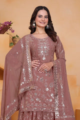 Woman wearing a mauve embroidered outfit with a matching dupatta against a beige background