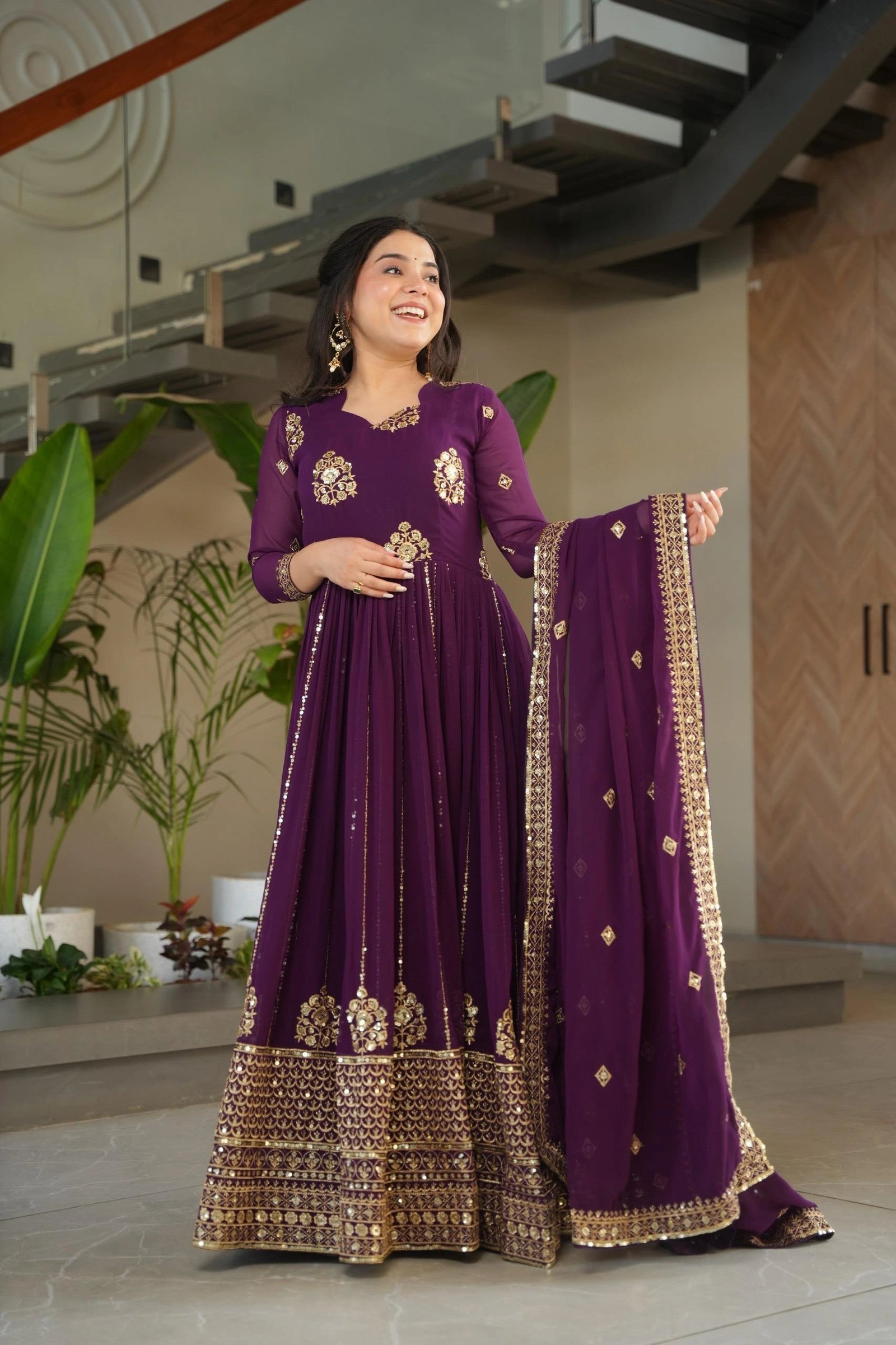 Woman in a purple traditional outfit with gold embroidery indoors.