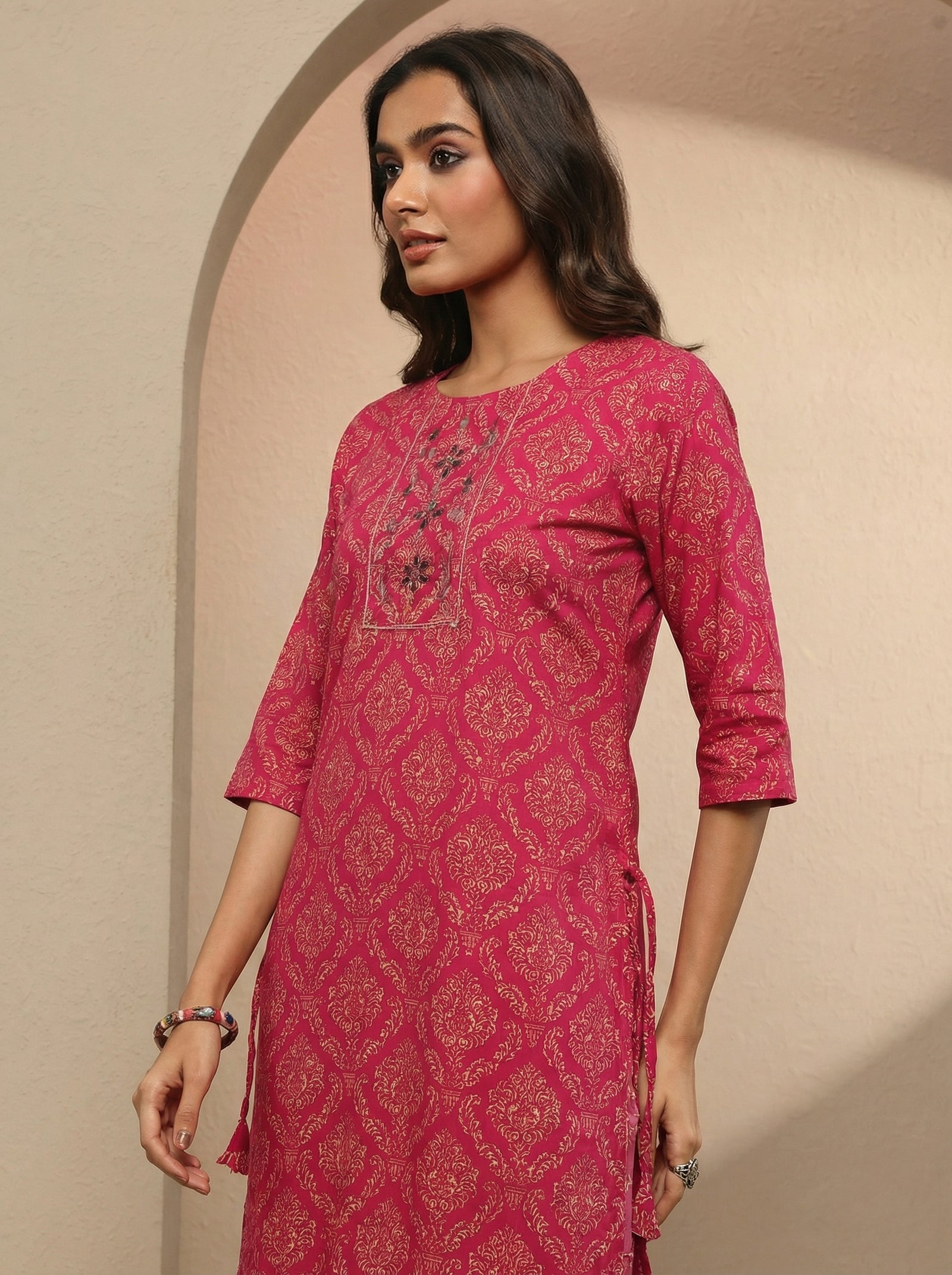 Woman wearing a pink patterned kurta against a beige background