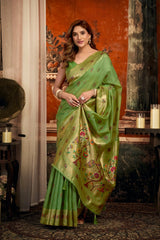 Woman wearing a green saree with floral patterns in an indoor setting.