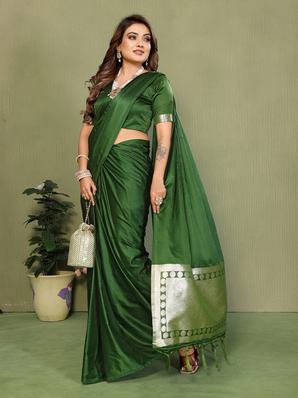 Woman wearing a green saree with a white border against a plain background