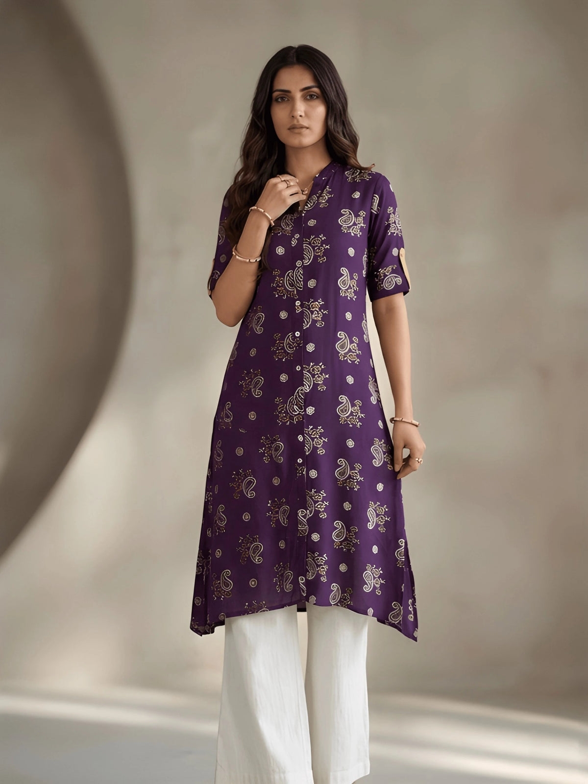Woman wearing a purple patterned kurta with white pants against a neutral background