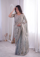 Woman wearing a silver saree with a mirror and white curtains in the background