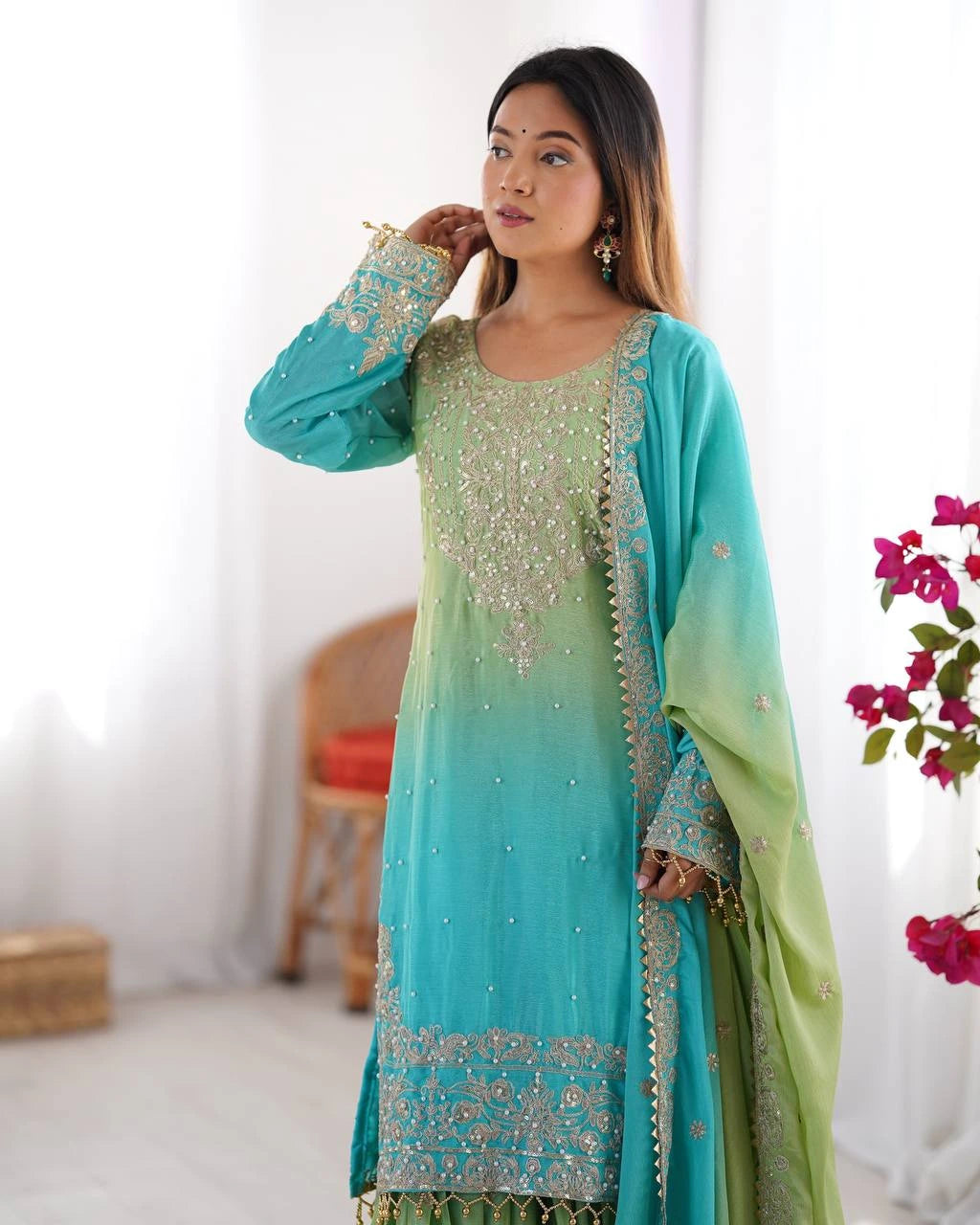 Woman wearing a green and blue embroidered traditional outfit with a blurred background