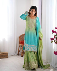 Woman wearing a green and blue traditional outfit with a white curtain background