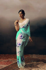 Woman wearing a light blue saree with floral patterns against a dark background