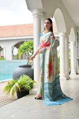 Woman in a floral saree standing by a poolside with white columns and greenery.
