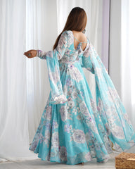 Woman wearing a floral dress with long sleeves in a room with white curtains.