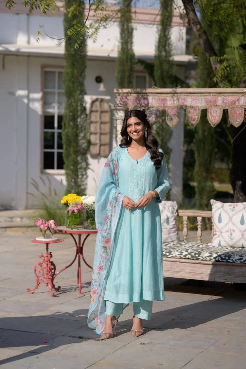 Woman in a light blue traditional outfit standing outdoors with decorative elements.
