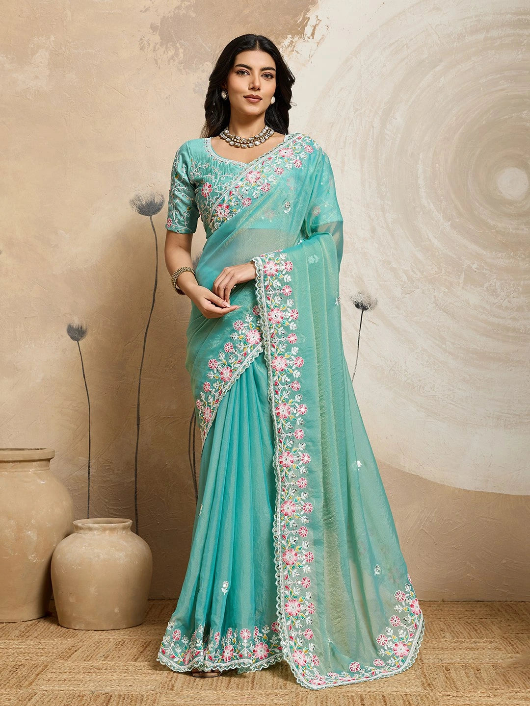 Woman wearing a light blue saree with floral embroidery in a neutral setting