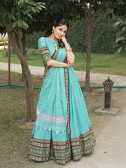 Woman in a traditional turquoise saree with a green background