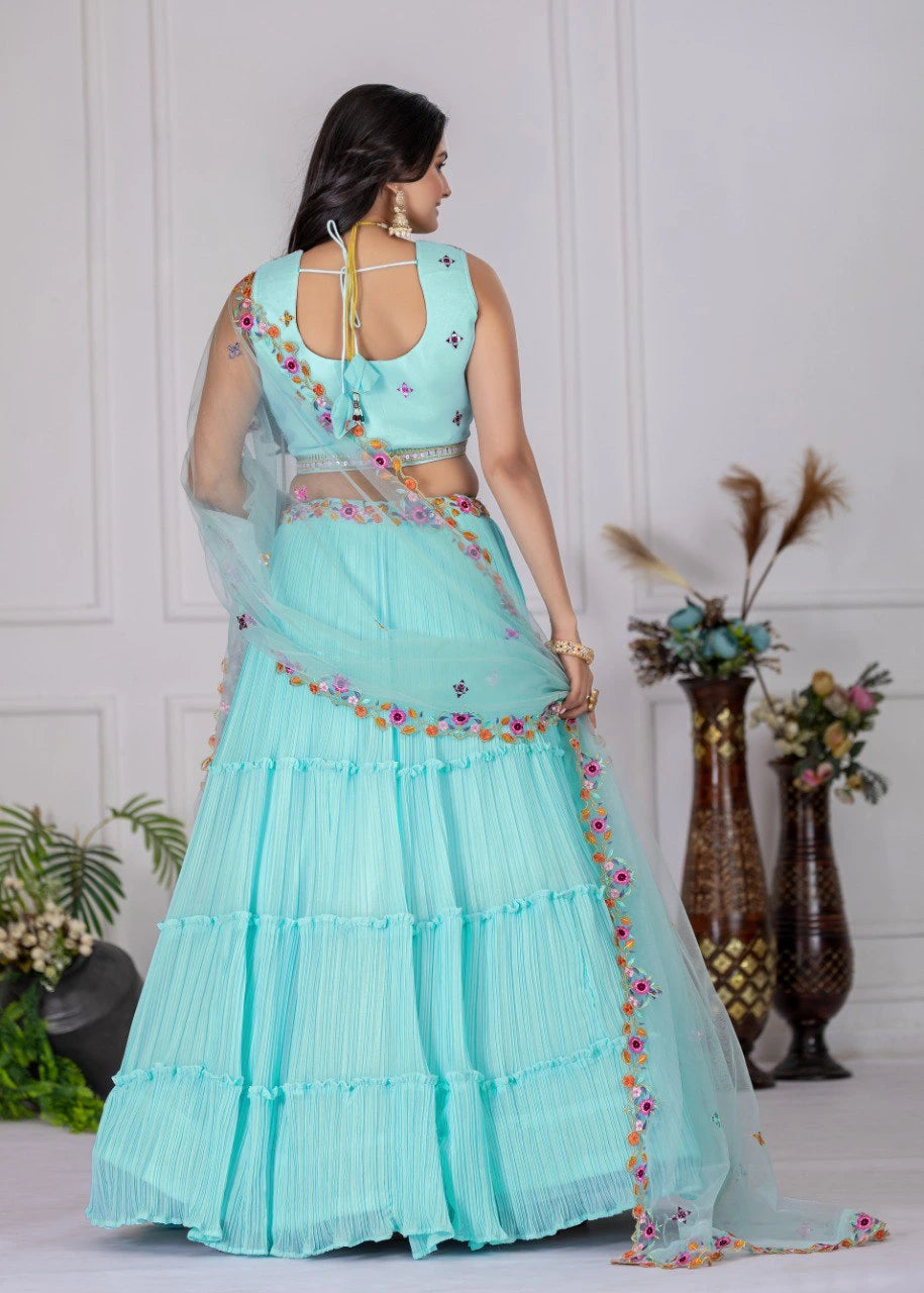 Woman wearing a light blue saree with floral patterns in a minimalistic setting.