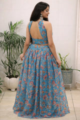Woman wearing a blue floral dress standing indoors with plants in the background