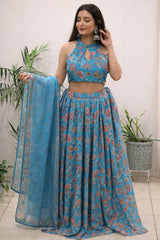 Woman wearing a blue floral outfit with a matching dupatta, standing indoors.