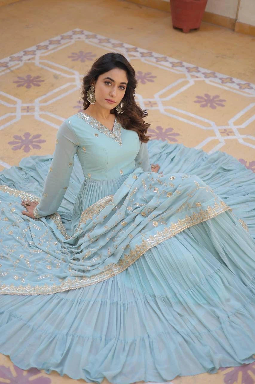 Woman in a light blue traditional outfit sitting on a patterned floor.