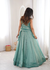 Woman in a teal dress standing in a room with white walls and a light-colored floor.