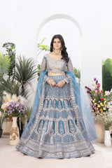 Woman in a blue and silver traditional outfit with floral decorations and plants in the background