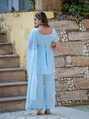 Woman in a light blue outfit standing on stone steps with a stone wall background