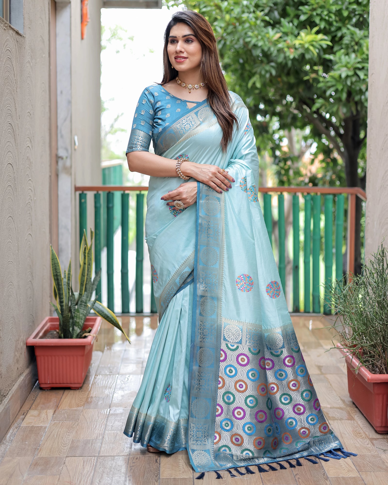 Woman wearing a light blue saree with a patterned border outdoors.