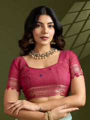 Woman wearing a pink blouse with gold jewelry against a green background