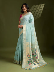 Woman wearing a light blue saree with floral embroidery on a green background