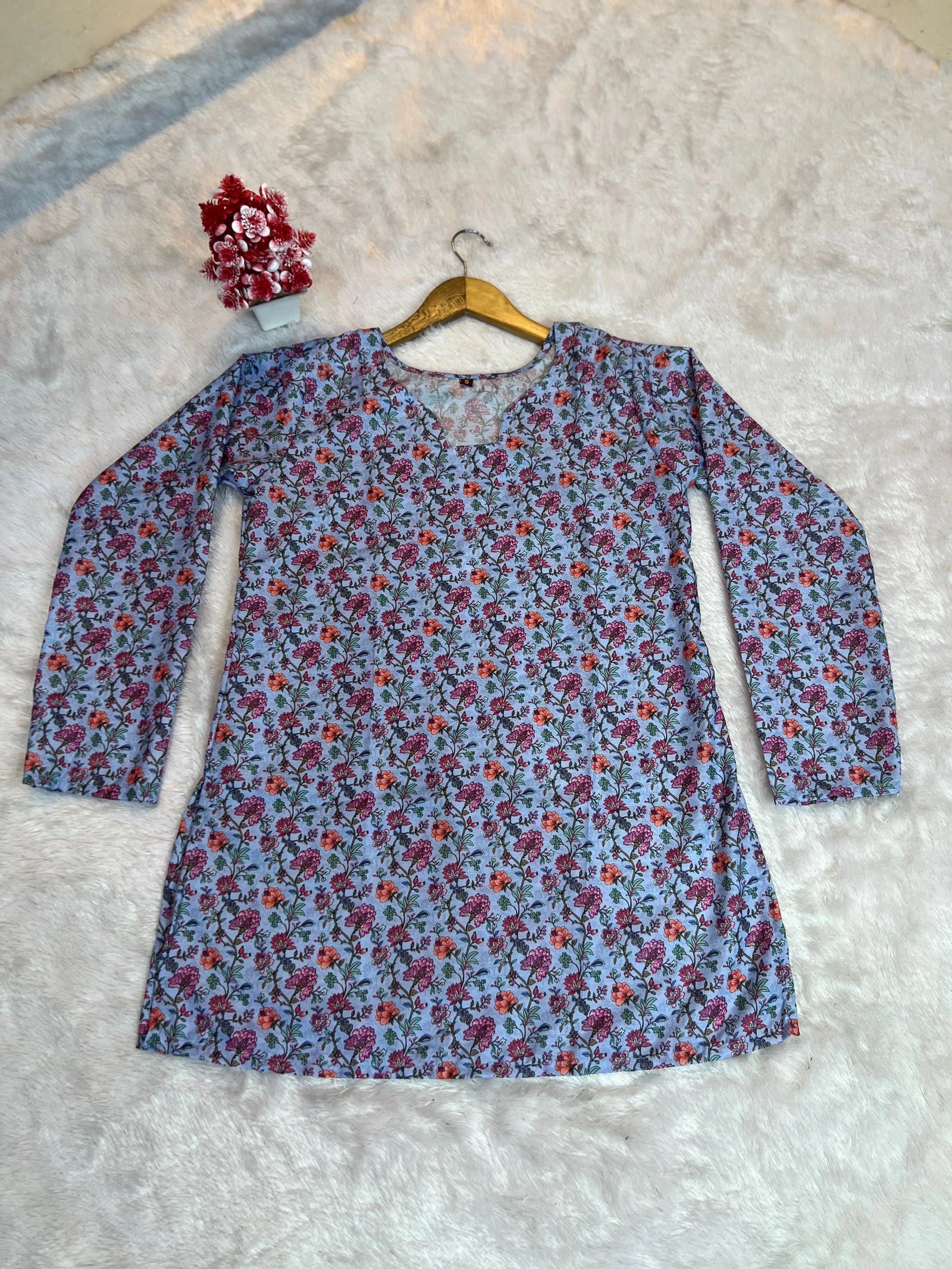 Floral dress on a hanger against a textured white background