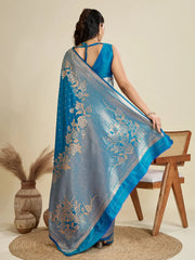 Woman holding a blue saree with floral patterns in a minimalistic setting