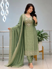 Woman wearing a green traditional outfit with embroidery in an indoor setting.