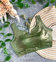 Green satin bralette on a textured surface with floral and woven mat elements.
