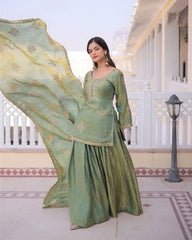 Woman in a green traditional outfit with a flowing dupatta in an outdoor setting.