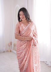 Woman wearing a pink saree with white patterns in a minimalistic setting