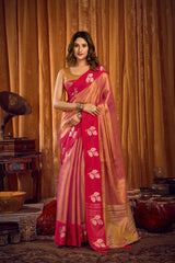 Woman in a pink and gold saree standing in front of a vintage record player and decorative items.