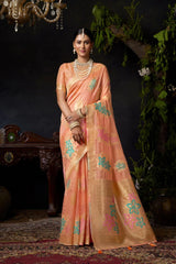 Woman in a peach saree with floral patterns standing in a decorated room.