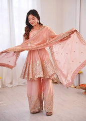 Woman wearing a pink and gold traditional outfit with a dupatta in a well-lit room.