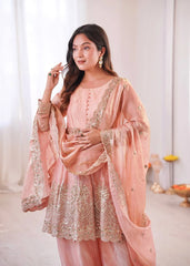 Woman wearing a peach embroidered traditional outfit in a bright room.