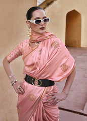 Woman wearing a pink saree with gold patterns in an outdoor setting.