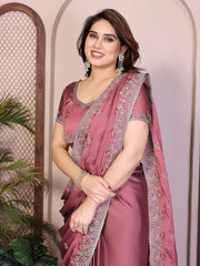 Woman wearing a pink saree with silver border against a neutral background