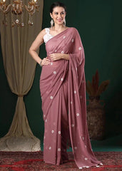 Woman wearing a mauve saree with white floral patterns against a dark background