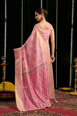 Woman in a pink saree with a black and white pattern, standing against a dark background.