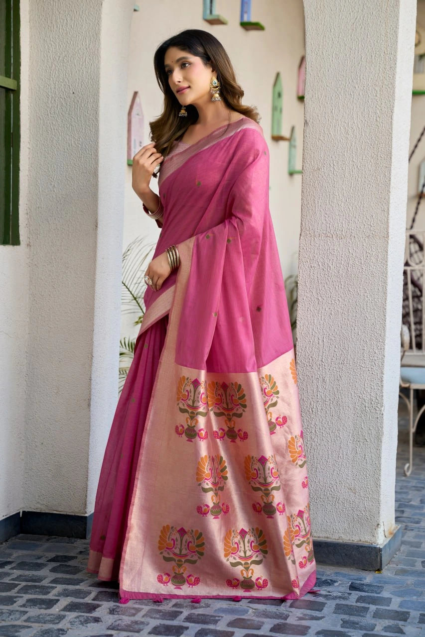 Woman wearing a pink saree with floral patterns indoors.